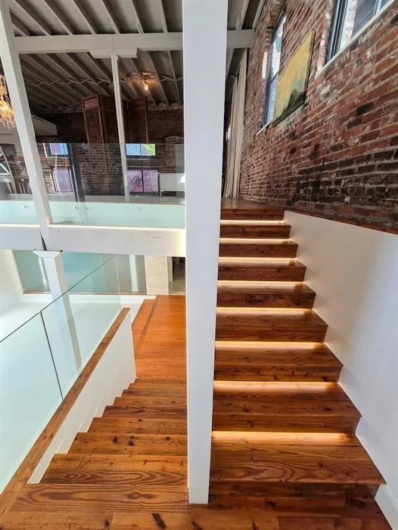 Wood-finish staircase with integrated step lighting and glass railing, virtual LED lighting