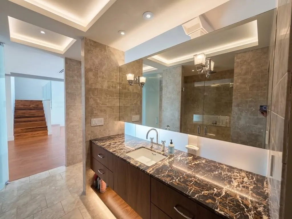 Vanity with integrated sink, dark wood-finish cabinetry, and a patterned countertop, virtual LED lighting