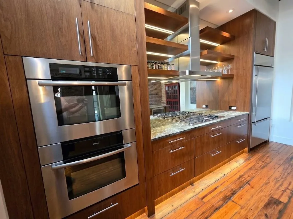 Integrated stainless steel double ovens, rich wood-finish cabinetry, under-cabinet lighting, stainless steel gas cooktop, and polished granite countertops, virtual LED lighting
