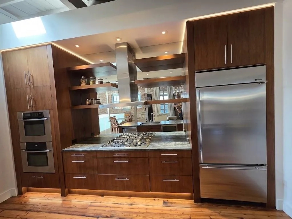 Custom wood cabinetry with under-cabinet lighting, stainless steel double oven, stainless steel range hood, built-in gas cooktop, and wood-finish flooring, virtual LED lighting