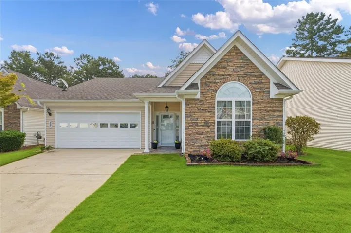 Stone veneer facade with an arched window, a single-car garage, and a concrete driveway