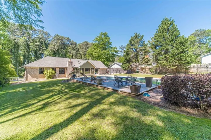 The property features a spacious backyard with an extensive lawn, a swimming pool, and a patio area