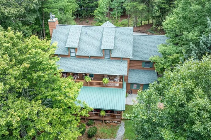 Wood-sided exterior with multiple dormer windows, a prominent brick chimney, and a multi-level deck