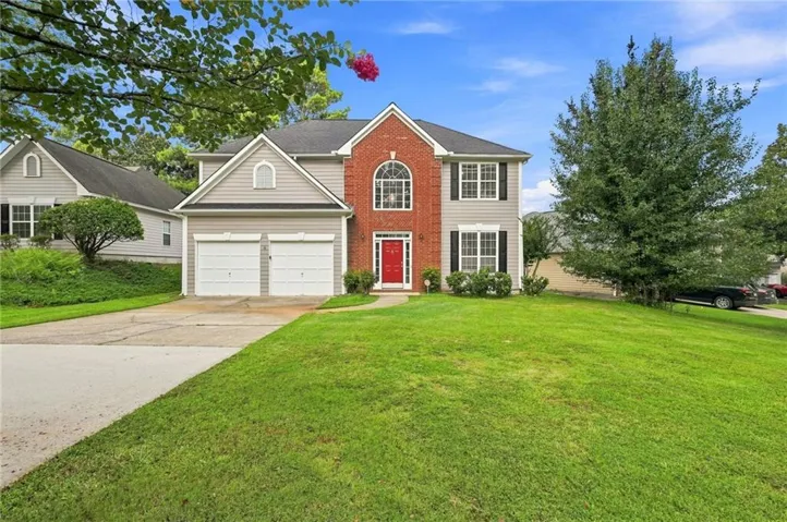 Two-story exterior with a red brick facade, light siding, a two-car garage, and a red front door
