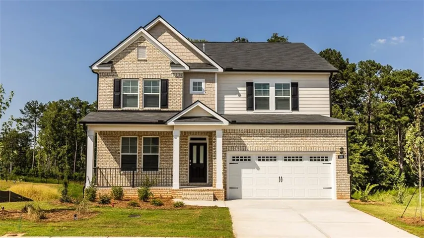 Two-story residence featuring a brick and siding exterior, covered front porch with columns, a two-car garage, and a concrete driveway