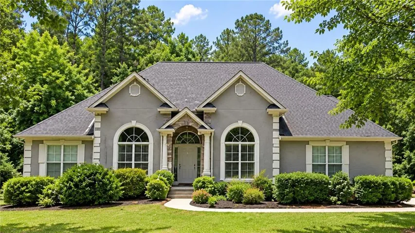 Stucco exterior with stone accents, arched transom windows, and a gabled roof
