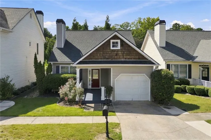 Front exterior with a covered porch, attached garage, and landscaped lawn