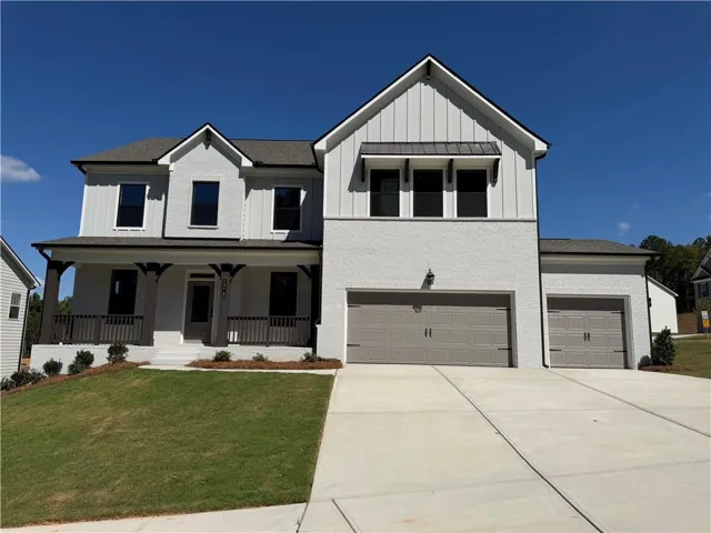 Two-story residence featuring a covered front porch, a multi-pane garage door, board and batten siding, and a gabled roofline