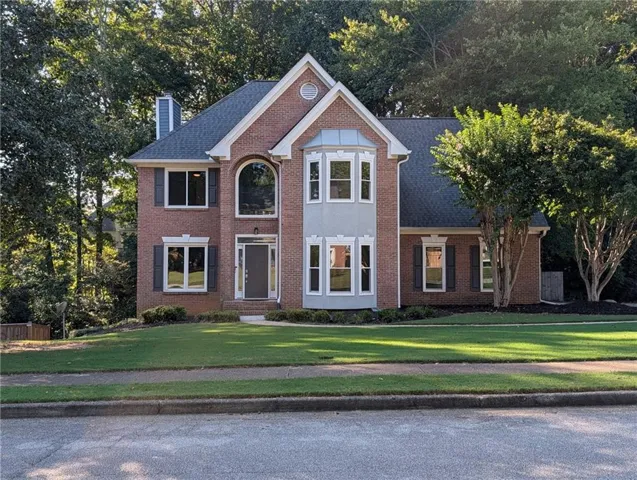 Brick exterior with a prominent front gable, bay window, architectural shingles, and a manicured lawn.