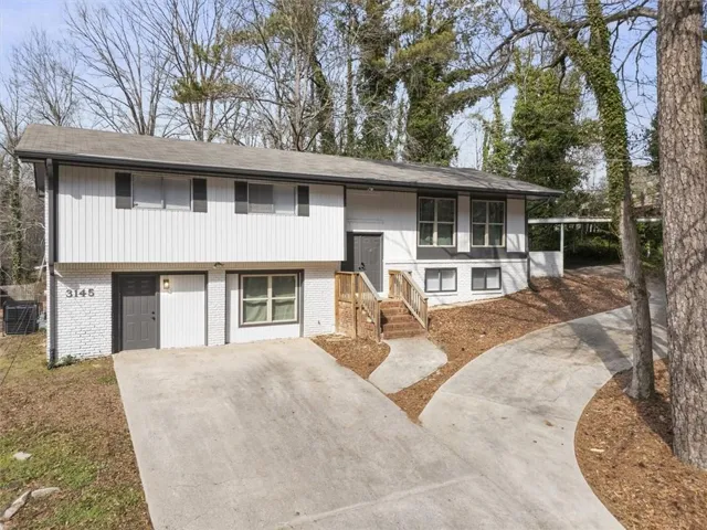 Bi-level home featuring brick siding, driveway, and roof with shingles