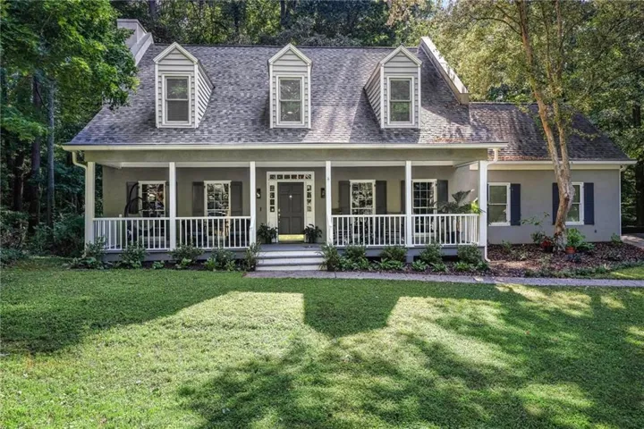 Traditional architecture with a covered front porch featuring white railings and columns