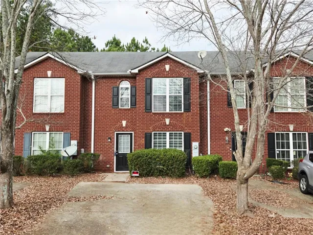 Brick exterior featuring white window grids, black shutters, and an arched window detail