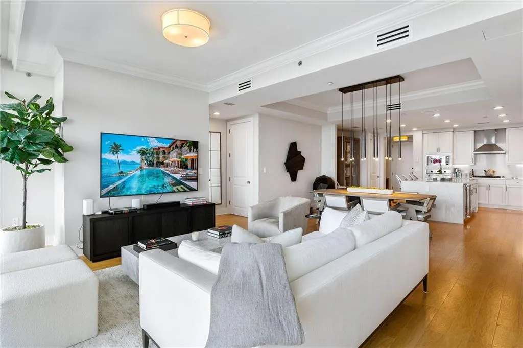 Living area with ornamental molding, a raised ceiling, light wood-style floors, and recessed lighting