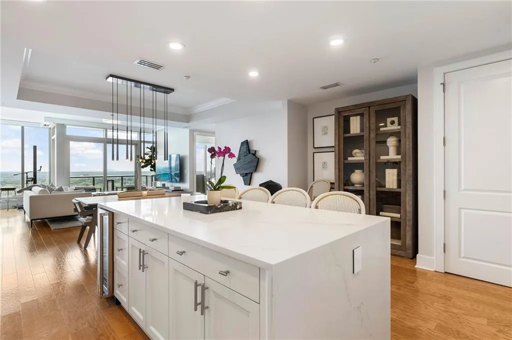 Kitchen with a raised ceiling, white cabinets, a breakfast bar, light wood-type flooring, and light stone countertops