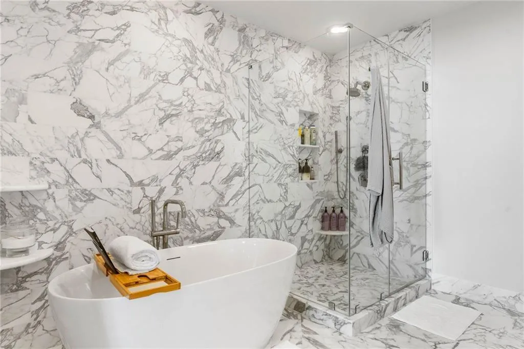 Full bath featuring a freestanding tub, tile walls, marble tiled floors, and a marble finish shower
