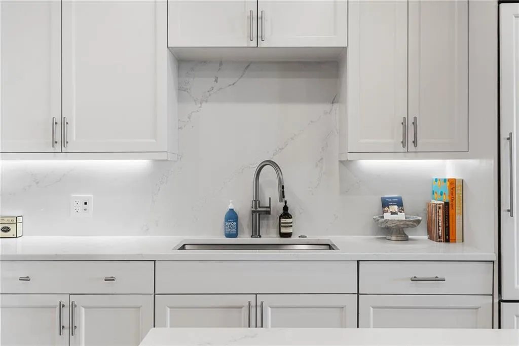Kitchen featuring white cabinets, light stone counters, and decorative backsplash