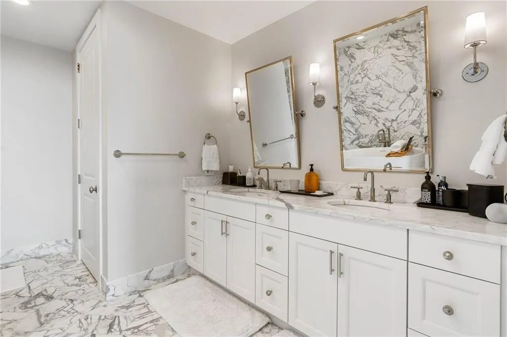 Bathroom featuring light marble finish flooring, double vanity, and a freestanding tub