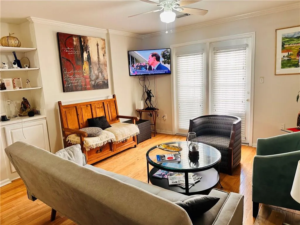 Living area featuring crown molding, light wood-style floors, and a ceiling fan