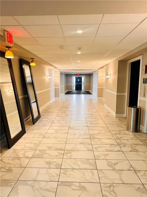 Hall with light marble finish flooring and a drop ceiling