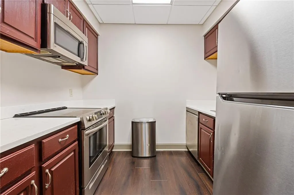 Kitchen featuring appliances with stainless steel finishes, a paneled ceiling, dark wood-style flooring, and dark brown cabinets