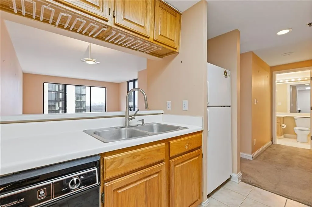 Kitchen with light countertops, dishwasher, freestanding refrigerator, light colored carpet, and recessed lighting