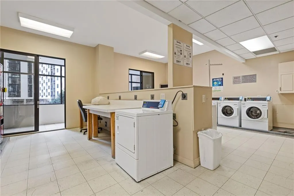 Shared laundry room with independent washer and dryer, plenty of natural light, and a drop ceiling