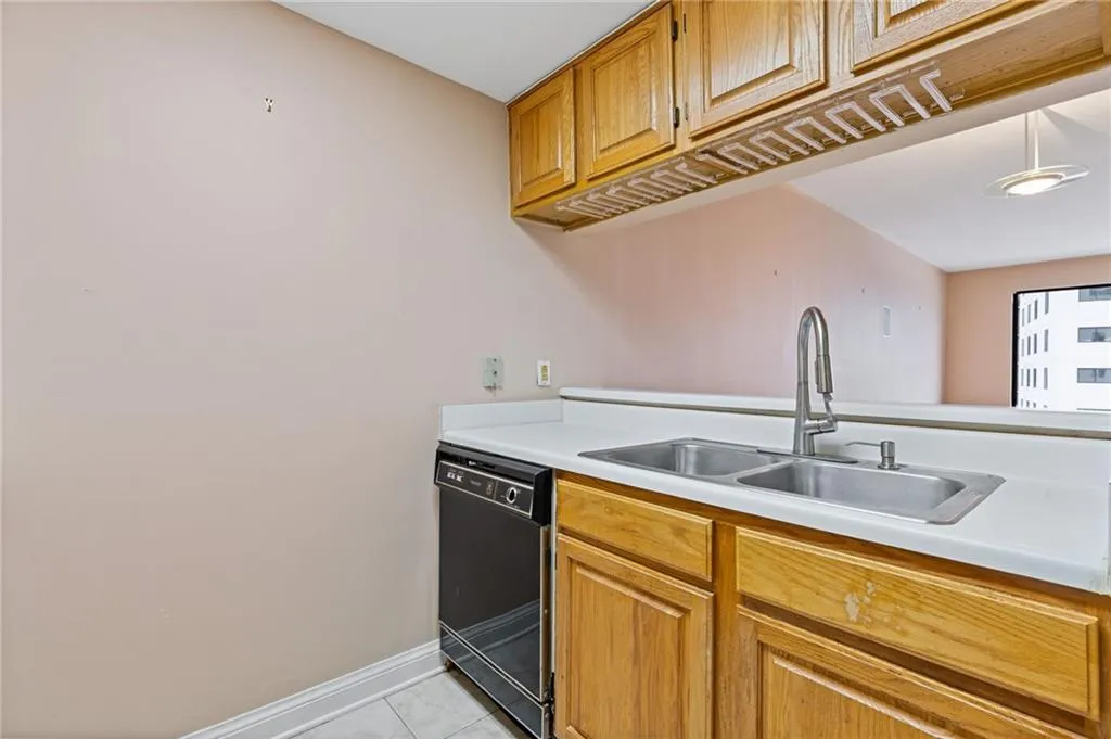Kitchen featuring light countertops, black dishwasher, brown cabinets, and light tile patterned floors