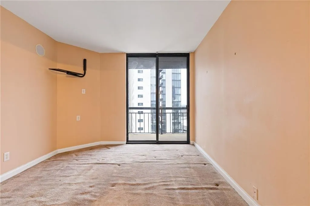 Carpeted empty room featuring floor to ceiling windows and baseboards
