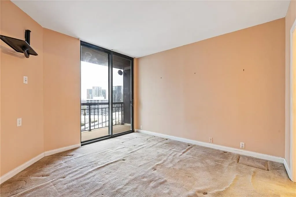 Carpeted empty room with a wall of windows and a city view