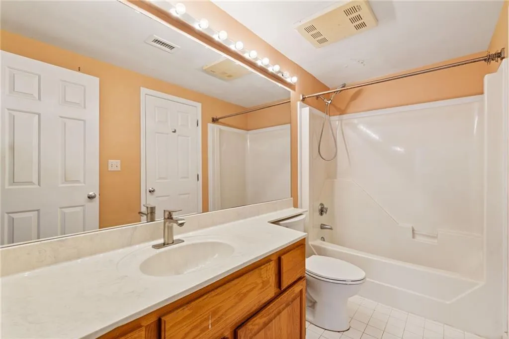 Bathroom with vanity, shower / bath combination, and light tile patterned floors