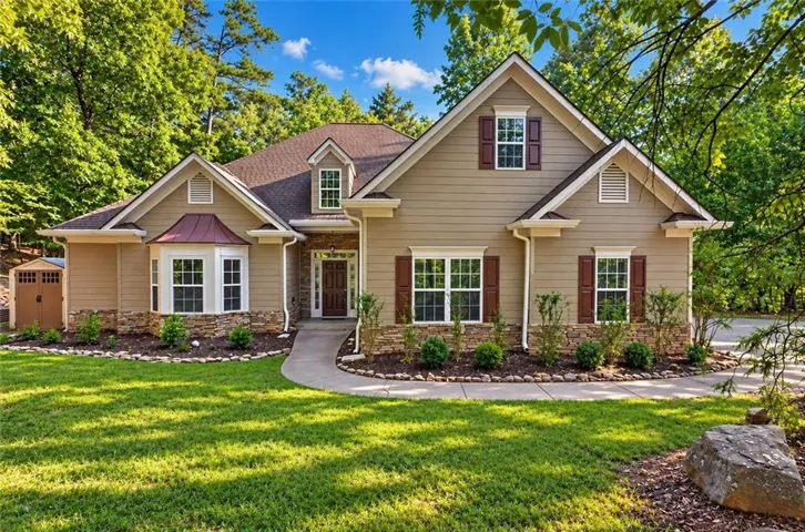 Elegant brick and stone colonial featuring a welcoming front portico, multiple gabled rooflines, and architectural detail work