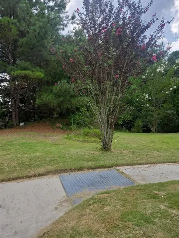 Green lawn with mature trees and a blooming shrub