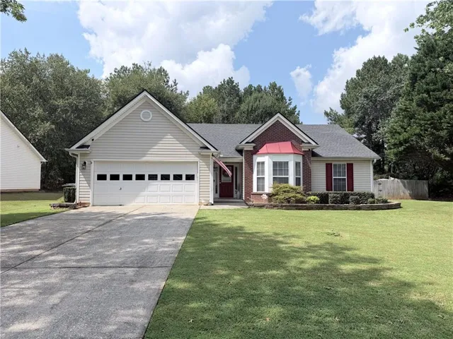 Single-story residence featuring a two-car garage, brick facade accents, a bay window, and a well-maintained front lawn