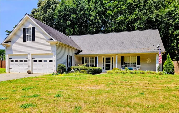Exterior featuring light-colored siding, a covered front porch with white columns, a two-car garage, and a gabled roofline