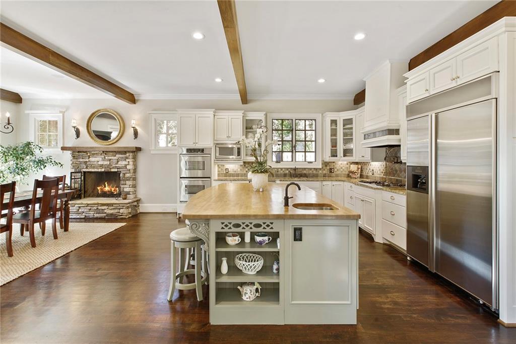 Such a bright kitchen to create and work in!  Beams and stacked stone fireplace add warmth and character.