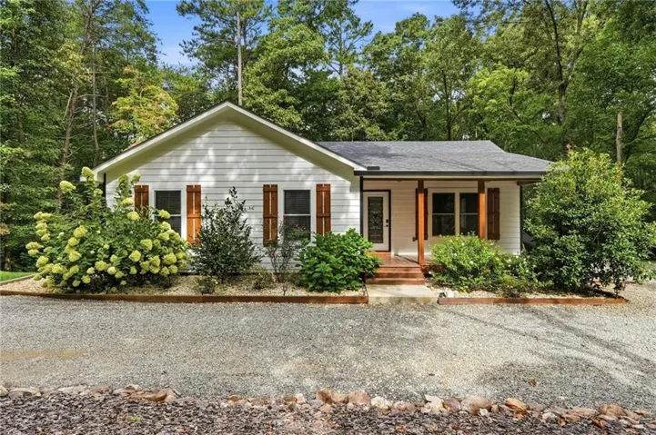 White siding exterior with a dark shingle roof and a covered front porch featuring wood support beams