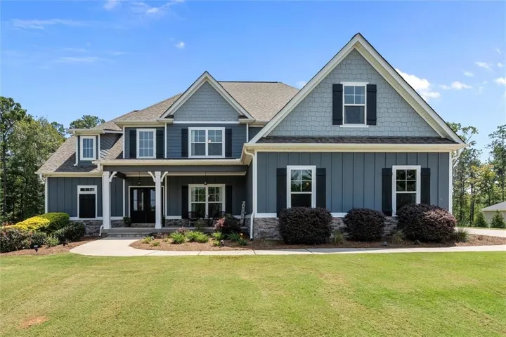 Elegant two-story Colonial featuring a striking dark blue exterior with contrasting stone accents and white trim