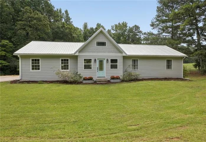 Ranch-style residence featuring light gray siding with white trim, a gabled entry with shake siding, and a light blue front door