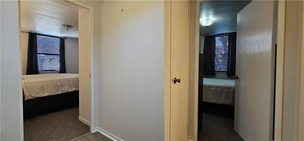 Hallway with dark colored carpet and baseboards Hallway with dark colored carpet and baseboards