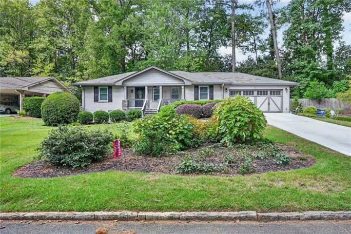 Ranch-style residence featuring a prominent front garden, a double-car garage, and an attached carport