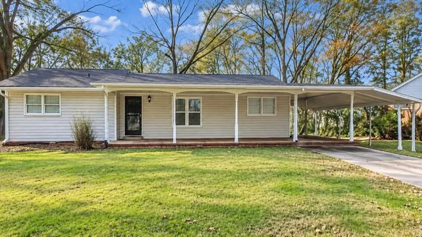 Single-story exterior with light-colored siding, a covered front porch, and a dedicated carport