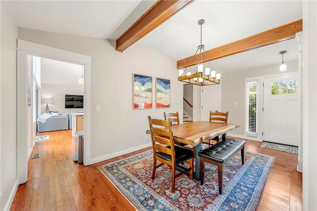 Kitchen featuring light wood-style floors, dishwasher, hanging light fixtures, light stone countertops, and high vaulted ceiling