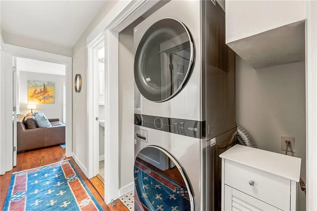 Washroom featuring stacked washer / drying machine and light wood-style flooring