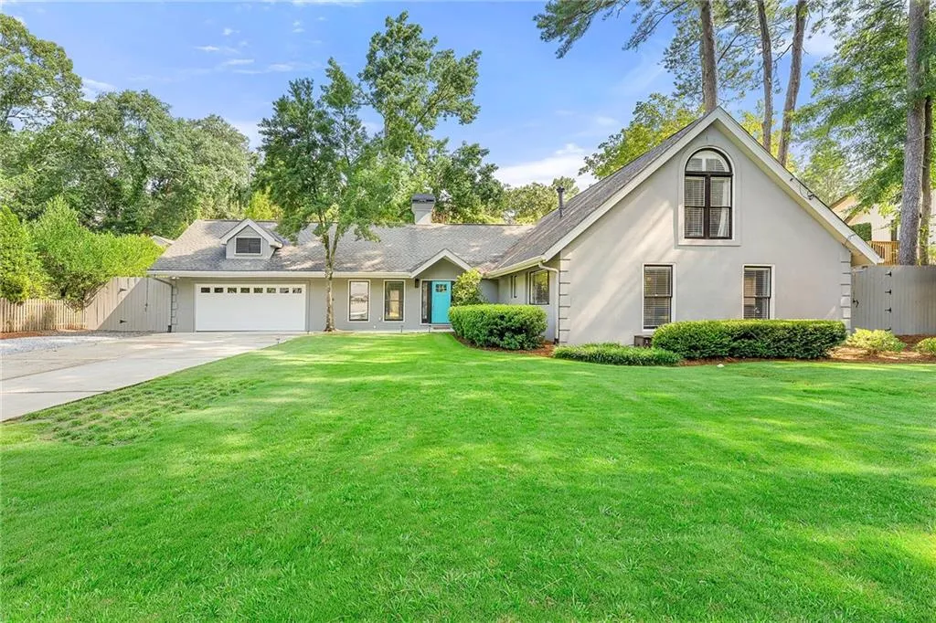 View of front facade featuring a gate, concrete driveway, an attached garage, and a chimney