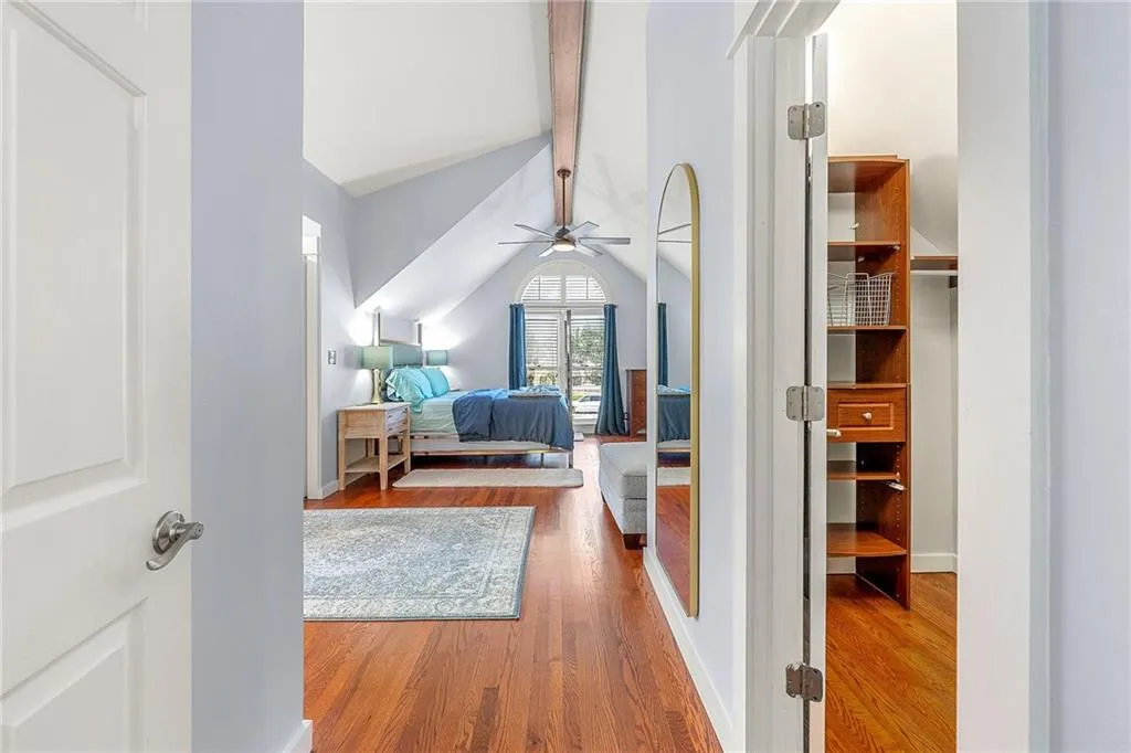Bedroom with wood finished floors, lofted ceiling, a closet, a ceiling fan, and a desk