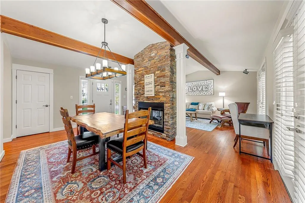 Dining space featuring light wood finished floors, a fireplace, and a chandelier, entrance door is in picture.