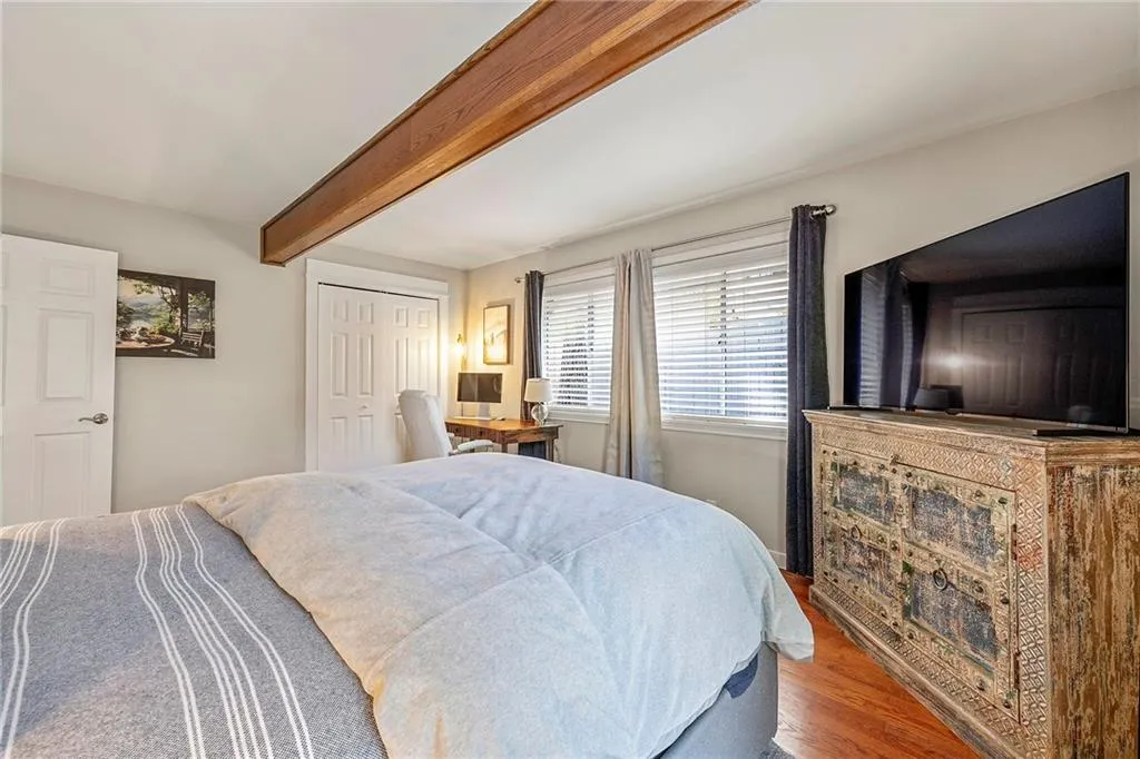 Bedroom with beam ceiling, wood finished floors, and a closet