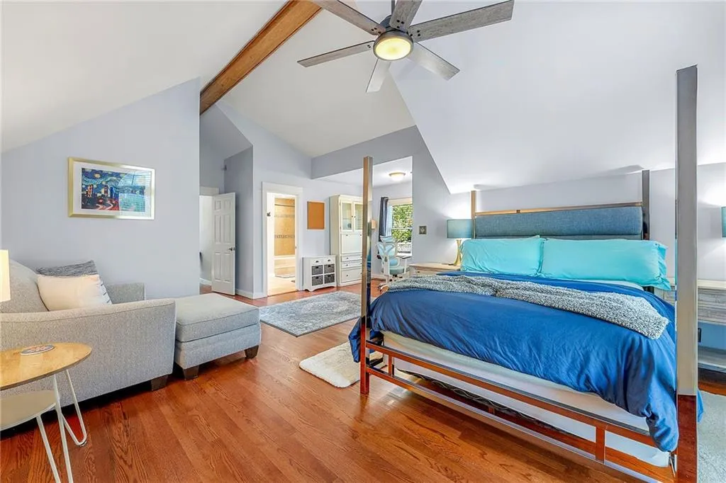 Bedroom with beamed ceiling, wood finished floors, high vaulted ceiling, ceiling fan, and ensuite bath