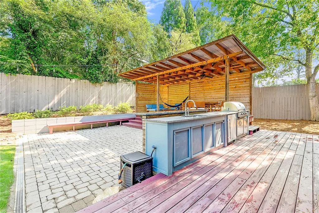 Wooden terrace featuring a fenced backyard, an outdoor kitchen, and a patio area