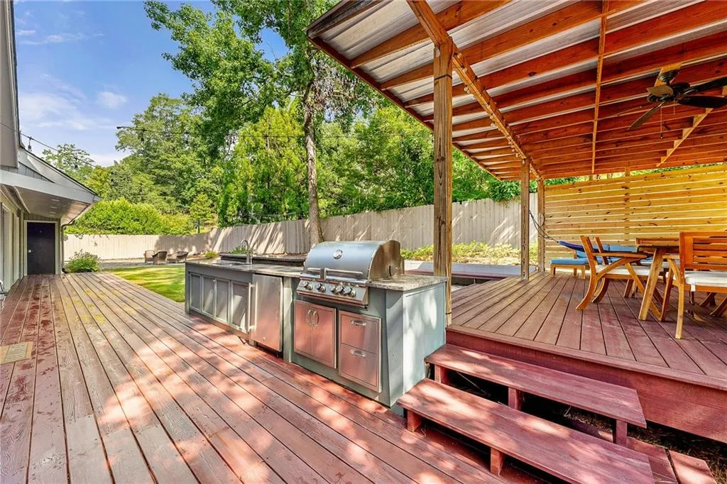 Wooden deck featuring outdoor dining area, a ceiling fan, and a fenced backyard